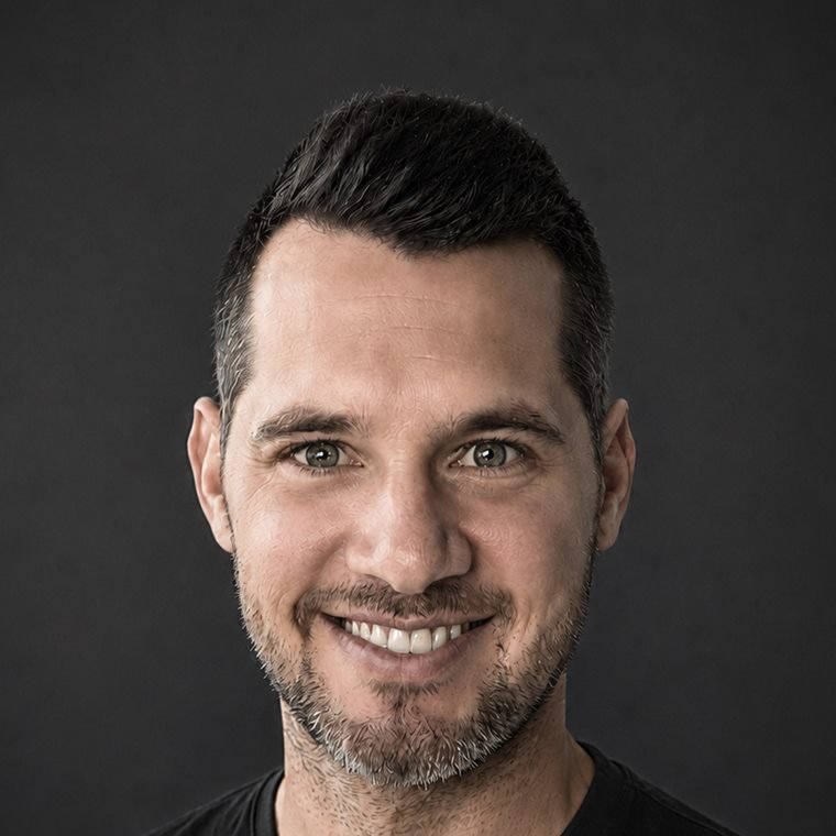 Tobias Schöppner lächelt in die Kamera, Schwarzweißaufnahme vor dunklem Hintergrund